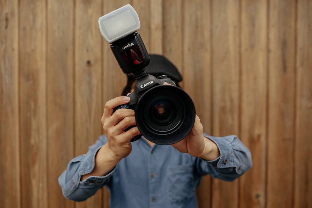 person holding black Canon camera - external flash photography